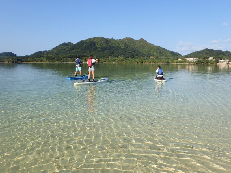 透明な海の上をSUPで並んで進む人たち